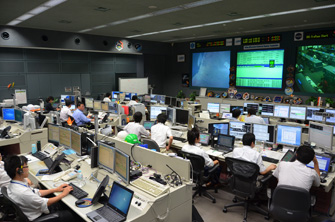 写真：運用中の「きぼう」の管制室です。彼らが24時間365日体制で「きぼう」を見守っています。
