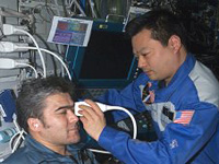 Using the ADUM protocols, ISS Expedition Commander Leroy Chiao performs an ultrasound examination of the eye on Flight Engineer Salizhan Sharipov. (NASA) 