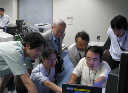 Professor Kamisaka (left rear) and the Space Seed team members checking the telemetry of the experiment at the User Operations Area (UOA) immediately after the experiment began