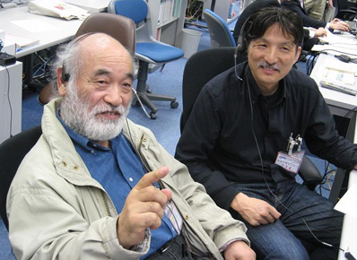 写真：実験運用管制室で実施の様子を見守るPIの福嶋先生（左）とCI（共同提案者）の今西先生（右）
