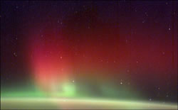 地球の大気の上に広がる緑と赤のオーロラ（撮影：第6次滞在クルーのペティット宇宙飛行士）
