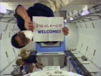 船内実験室へ入室直後の星出宇宙飛行士。手持ちの紙には「いらっしゃ～い！！WELCOME」の文字
