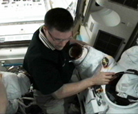 船外活動ユニット（EMU）の準備を行うウィーロック宇宙飛行士（出典：JAXA/NASA）