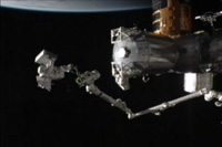 SSRMSの先端に乗ってMBSUを運ぶ星出宇宙飛行士（出典：JAXA/NASA）