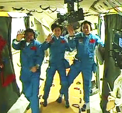 天宮1号内の3人の宇宙飛行士。天井や床の紐状の固定具や室内の様子がうかがえる。（提供 CCTV）
