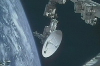 写真：ISSのロボットアーム（SSRMS）の先端に乗り、Kuバンドアンテナを運ぶ船外活動クルー