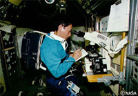 生体データ記録装置を背負ってミッション作業を行う毛利宇宙飛行士
