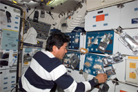 スペースシャトルのギャレー（調理設備）で食事の準備をする土井宇宙飛行士